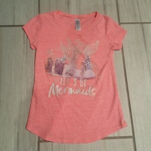 A pink shirt with mermaids on it